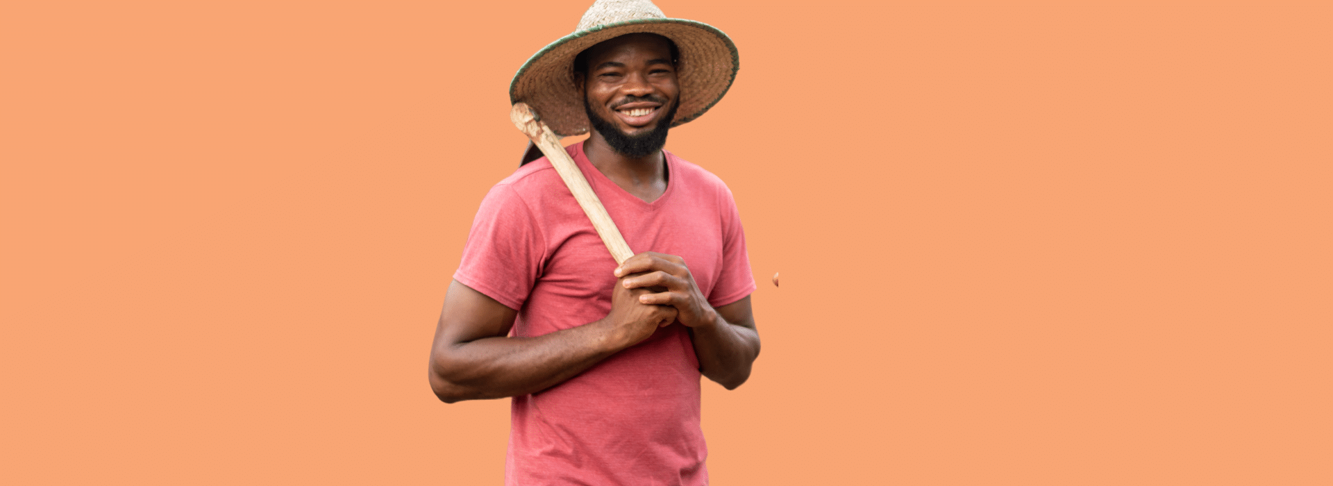 Agricultor com chapéu de palha e segurando uma enxada apoiada no ombro enquanto sorri para a câmera