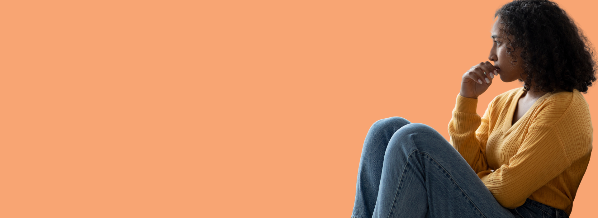 Mulher deprimida e pensativa está sentada de lado com mão no queixo