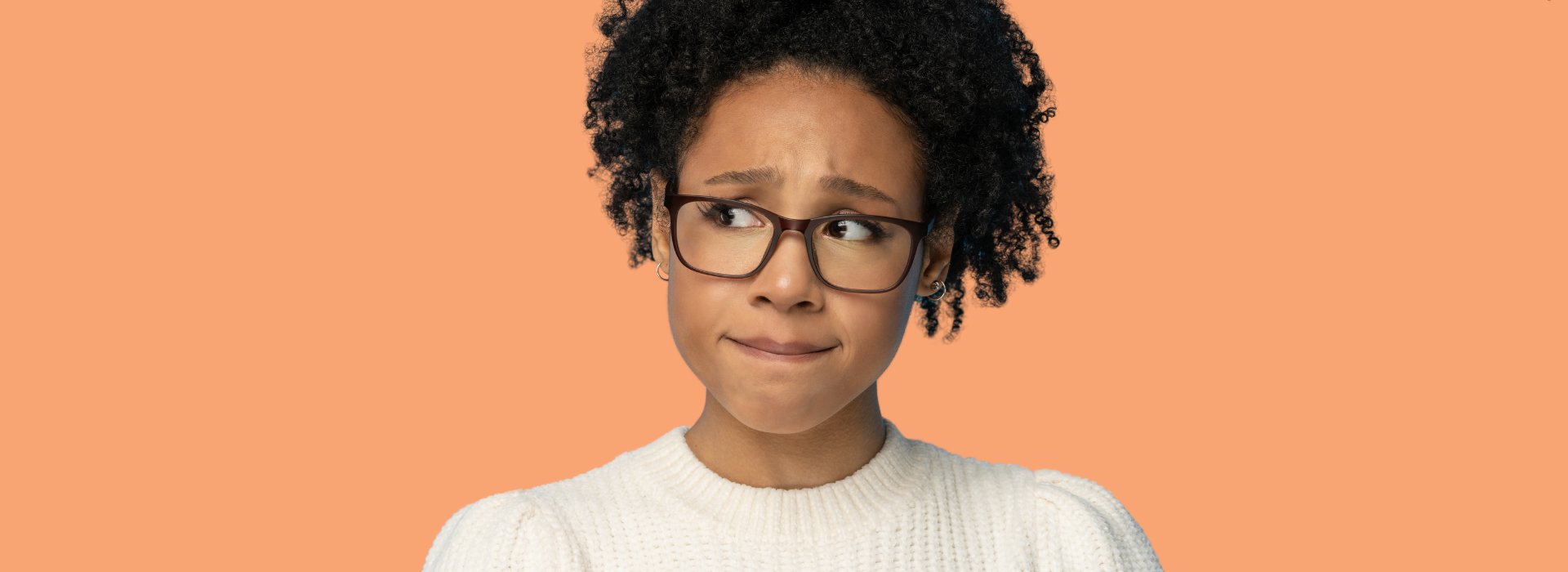 Foto de Capa: Mulher olha preocupada para o lado enquanto morde o lábio de nervosismo