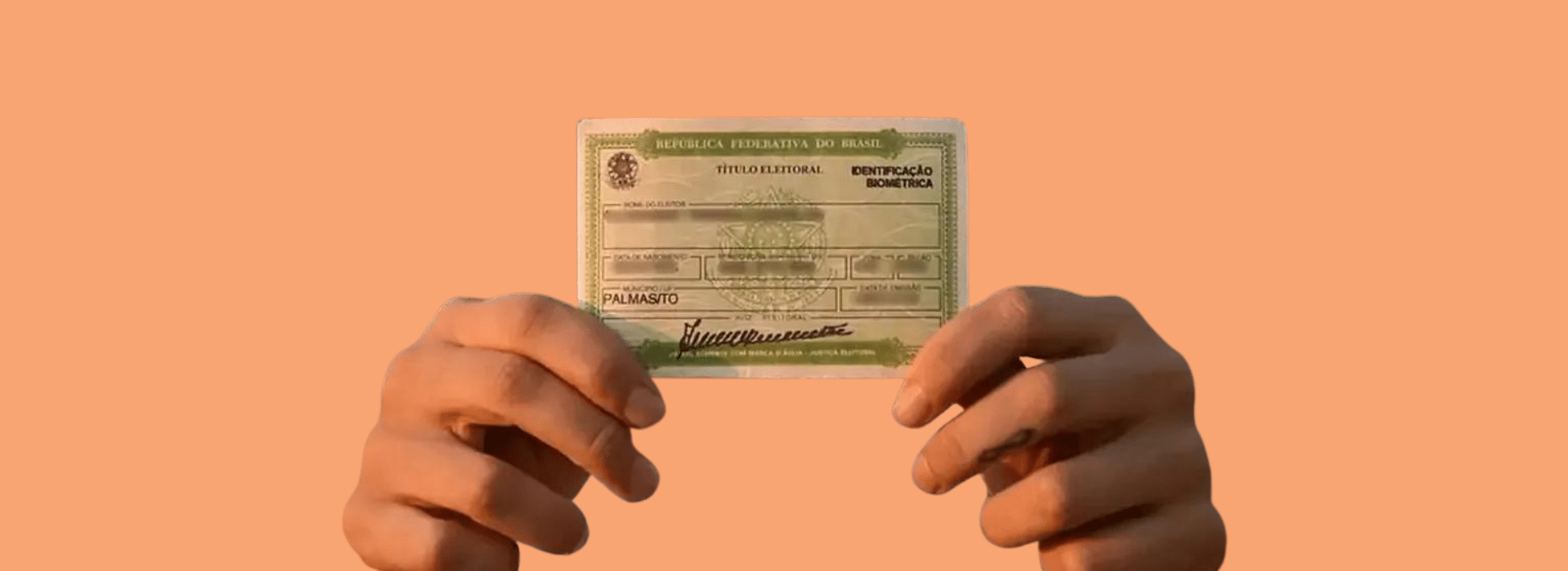 Foto de Capa: Duas mãos seguram um título de eleitor